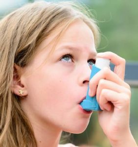 a young girl using an inhaler